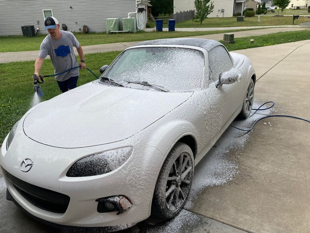 Washing a white sports car with a hose